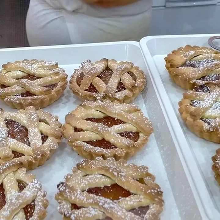 Crostatine con la griglia di pasta frolla e la marmellata, ancora sulla carta da forno.