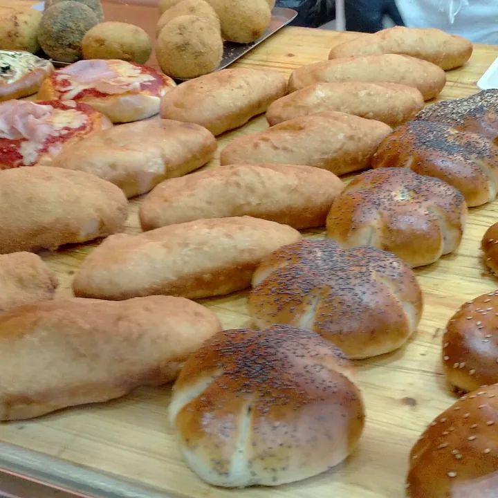 Un tagliere di rustici siciliani: bocconcini al sesamo, focaccine e sfincione tagliato a pezzi.
