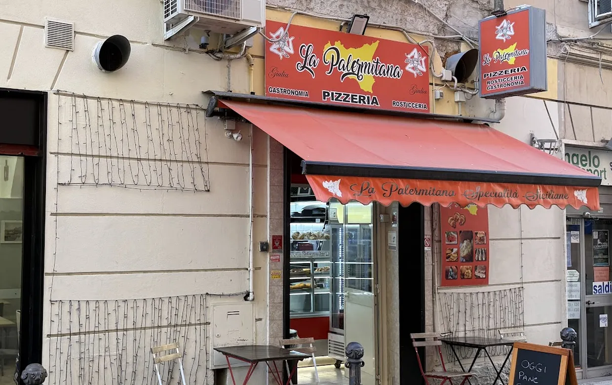 L'ingresso in via Luciano Manara: l'insegna rossa La Palermitana, la tenda con la scritta Specialità Siciliane, i tavolini sul marciapiede e la lavagna del giorno.